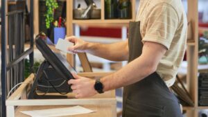 Side view portrait of bearded cafe worker using register while processing orders in green eco friendly interior